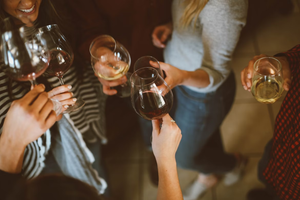 Friends toasting wine: Top view of group saying cheers. Celebration with red and white wine glasses at a casual party.