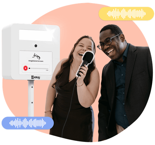 Two happy people holding a microphone in front of a KRUU photo booth, using the audio feature.