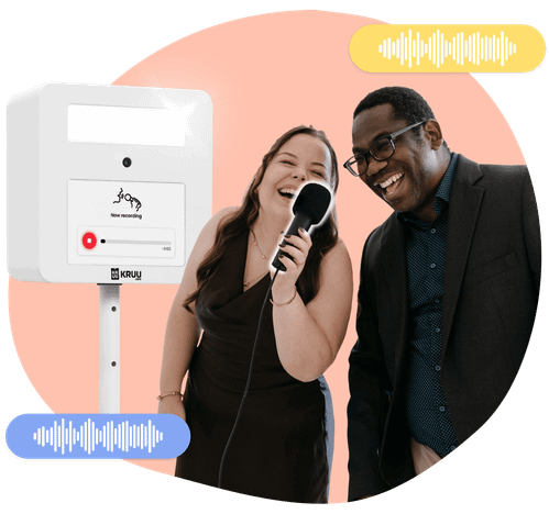 Two happy people holding a microphone in front of a KRUU photo booth, using the audio feature.