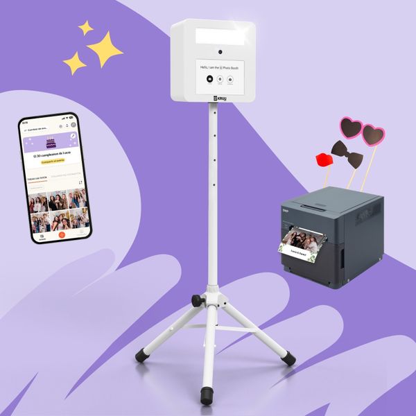 Un diseño de producto sobre fondo morado con un fotomatón KRUU blanco sobre un trípode. A la izquierda, un smartphone muestra una galería de eventos con temática de cumpleaños dentro de la aplicación KRUU. A la derecha, una impresora DNP gris oscuro muestra una foto recién impresa de unos amigos en una fiesta. Sobre la impresora, hay montados tres accesorios fotográficos, como unas gafas con forma de corazón, una pajarita y una boca que besa.